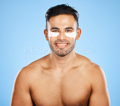 Buy stock photo Beauty, skincare and eye patch with grooming and man in wellness for skin portrait against blue studio background. Eye care, healthy face and fresh glow with smile, clean with hygiene and cosmetic.