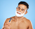 Shaving, grooming and hygiene, man with razor for clean and fresh face, cream and foam product with blue studio background. Facial wellness, healthy skin and skincare, beauty and check blade.