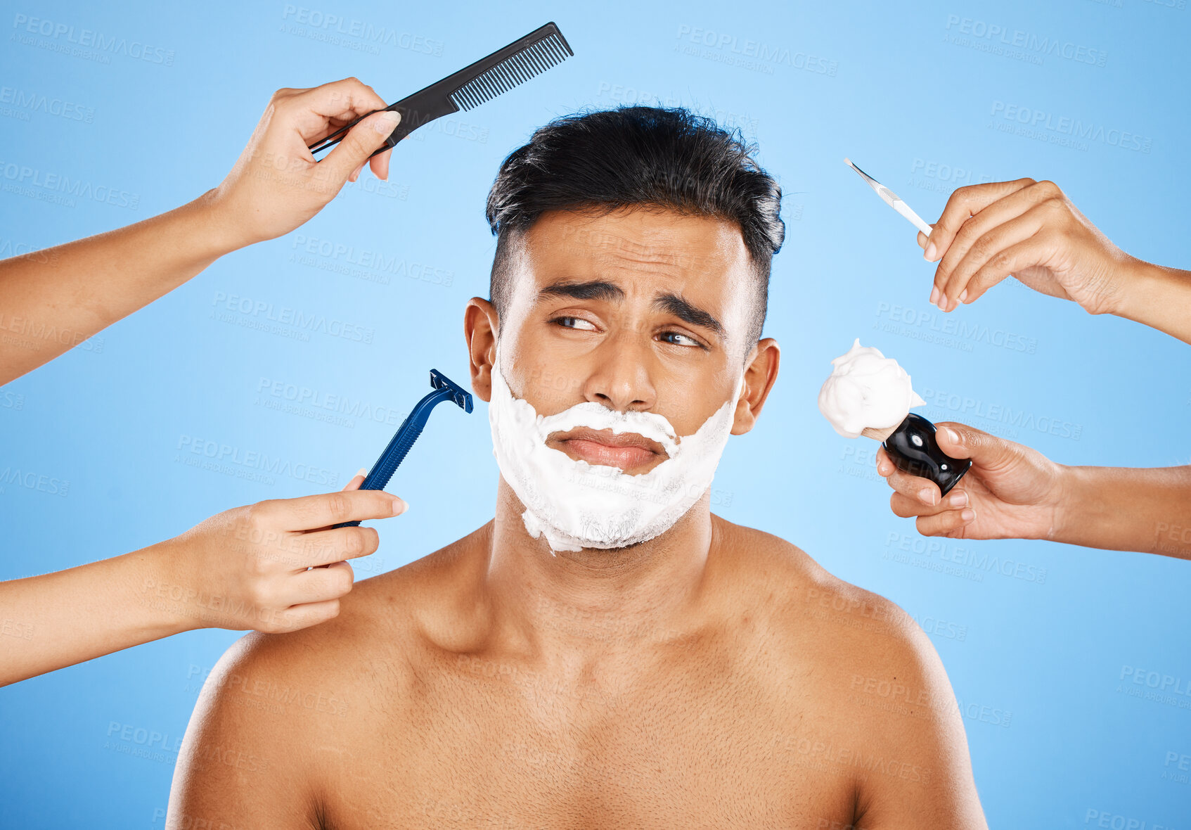 Buy stock photo Face, shave and grooming with hands holding equipment for shaving or brushing hair in studio on a blue background. Skincare, wellness and luxury with an unhappy male customer at the barber for beauty