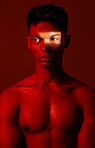 Beauty, red light and man in studio for health, wellness and skincare with a spotlight reflection. Body, self care and healthy male model from Mexico with cosmetics isolated by a brown background.