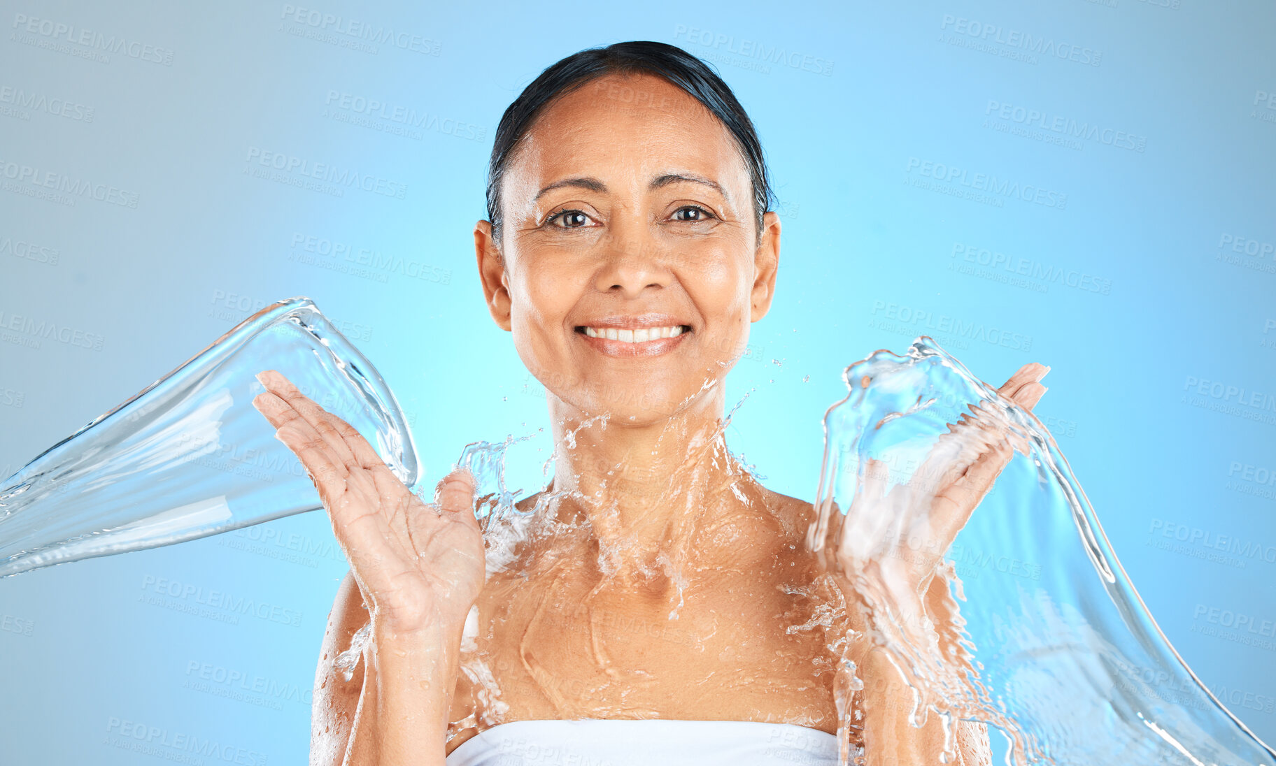 Buy stock photo Water splash, woman and beauty portrait on blue background, skincare or facial wellness, body care and shower, cleaning and personal hygiene. Mature studio model, water stream and aesthetic hydration