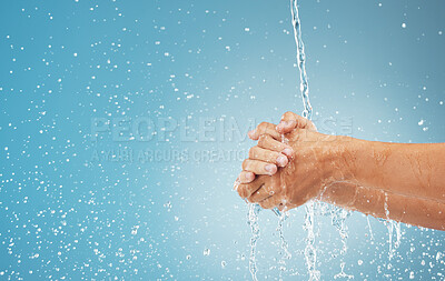 Buy stock photo Water splash, cleaning hands and hygiene on blue background, advertising or product placement space. Health, skincare and safety from germs or bacteria, man washing hand in water in studio background