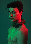 Beauty, art and portrait of man with snake on neck in neon studio, danger and creative style. Skincare, color and lights, seductive male fashion model with sexy look on green background and red light