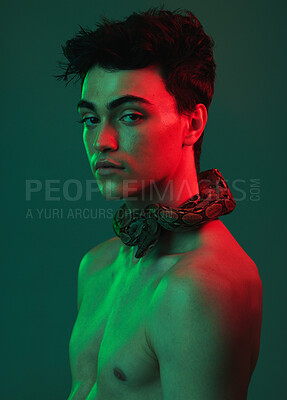 Buy stock photo Beauty, art and portrait of man with snake on neck in neon studio, danger and creative style. Skincare, color and lights, seductive male fashion model with sexy look on green background and red light