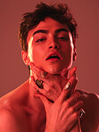 Beauty, cosmetics and man in studio with red lighting to model with jewellery, makeup and designer rings. Creative art, lgbt and portrait of young male pose for skincare, beauty products and fashion
