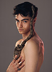 Portrait, man and model with snake in studio isolated on a gray background. Beauty, art and fashion of young male model posing with python, reptile or serpent for skincare, body care and cosmetics.