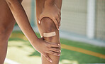Woman athlete, knee pain and sport injury outdoor with bandaid with. inflammation, joint and bad accident. Girl holding leg, muscles tear and joint swelling or muscle fatigue in a sports competition