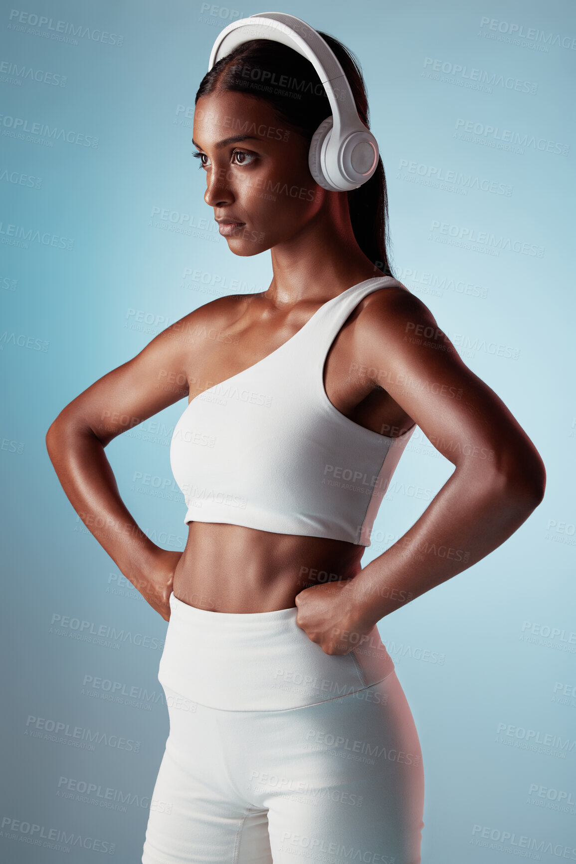 Buy stock photo Fitness, studio and woman streaming music ready to start training, workout and body exercise in India, Mumbai. Focus, blue background and healthy girl athlete listening to radio or mindset podcast