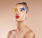 Makeup, clown and young woman with facial art, natural beauty and wellness with brown studio background. Artist, female and girl being creative, with pride and confident with cosmetics or face paint.