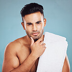 Skincare, health and face of model from India posing for health, wellness and dermatology after cleaning, facial or shaving against blue background. Portrait of beauty man with towel for self care