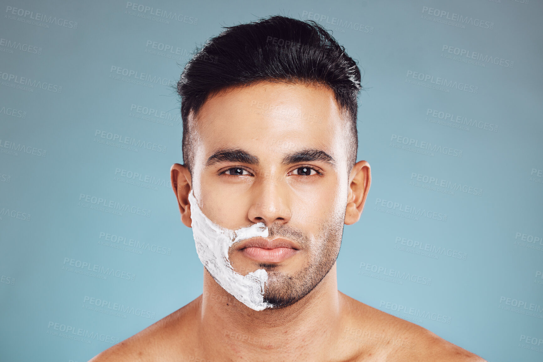 Buy stock photo Shaving cream, face and portrait of man in a studio to shave his beard with foam or creme. Beauty, skincare and model from Puerto Rico grooming or cleaning his facial hair isolated by blue background