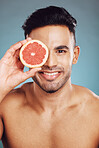 Happy studio portrait, grapefruit man for skincare wellness beauty and face smile health against wall. Young cosmetics model, fruit happiness for healthy facial skin or vitamin c with blue background