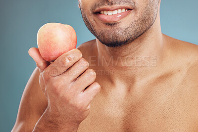 Buy stock photo Hand, apple and beauty with a man model in studio on a blue background for heathy eating or diet. Food, fruit and health with a young male posing with a nutrition snack for natural care or vitamins
