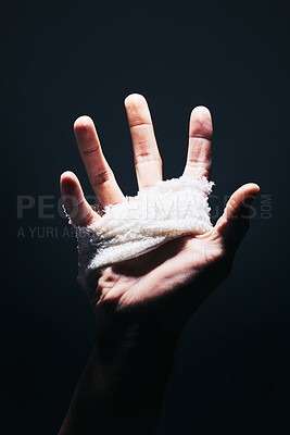Buy stock photo Bandage, black and hand palm of man with medical injury pain, first aid care and hurt from mma fight, boxing or crime violence. Shadow light, dark trauma wound and sports boxer with injury spotlight