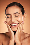 Face, beauty smile and woman with eyes closed on brown studio background. Makeup, skincare and female model from Australia with hands on face for smooth skin routine, perfect teeth and wellness.
