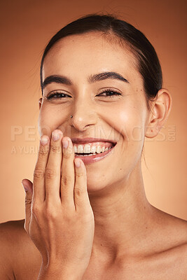 Buy stock photo Skincare, hand and woman in studio for skin, makeup and beauty on orange background, happy and relax. Hand, portrait and face of indian wellness model smile for secret, cosmetic and product mockup