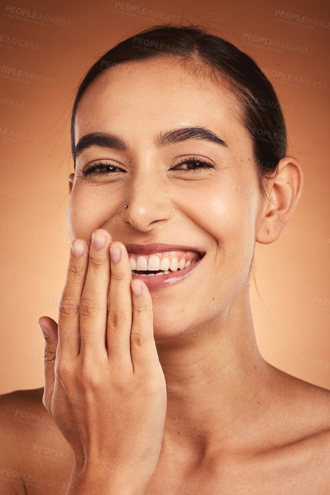 Buy stock photo Skincare, hand and woman in studio for skin, makeup and beauty on orange background, happy and relax. Hand, portrait and face of indian wellness model smile for secret, cosmetic and product mockup