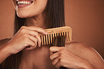 Woman combing hair, closeup smile and cosmetic face beauty for model with orange studio background. Hair care health, happy cosmetic girl and wood recycle comb for wellness with natural healthy locks