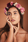 Beauty, hair flowers and woman in makeup on orange studio background. Floral cosmetics, skincare and young, elegant and thinking female model, posing with roses or plants for healthy skin treatment.
