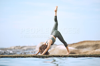 Buy stock photo Yoga, stretching and black woman doing exercise at the beach, in yoga pose by water and rocks. Fitness, motivation and girl doing workout, training and exercising by sea for peace, wellness and calm
