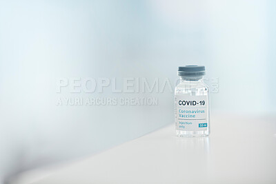 Buy stock photo Covid, vaccine and medication with a bottle of a liquid on a table in the hospital as a cure or treatment. Healthcare, pharmacy and medicine in a corona research lab for pharmaceutical development