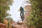 Mountain bike, sports and fitness with a man adrenaline junkie riding in the woods or forest in nature. Sky, training and exercise with a male athlete on a bike for trail riding or adventure 