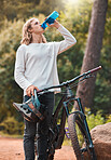 Drinking water, bike sport and man on an outdoor forest nature trail for exercise and sports. Bicycle training, cycling workout and fitness of an adventure athlete on a woods dirt road for wellness