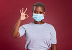 Black woman, covid and ok sign with face mask for approval, yes and safety with hand gesture for health and wellness. Portrait of African model for covid 19, corona and virus compliance in studio
