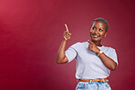 Black woman, mockup and pointing in advertising, sale or marketing with smile against a studio background. African American female in advertisement with empty copy space for message, text or brand