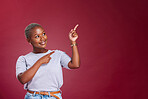 Black woman, mockup and pointing for advertising, marketing or banner against a studio background. Happy African American female point to empty copyspace for sale advertisement text, message or brand
