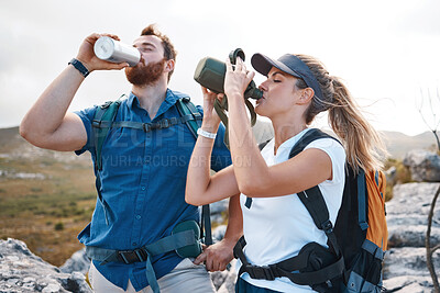 Buy stock photo Water, hiking and couple trekking in the mountains for travel, peace and adventure during summer. Thirsty, tired and young man and woman with a drink from a bottle while walking in nature for holiday