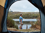 Man by lake from tent view, outdoor and camping for adventure, vacation or holiday in nature. Explorer, binocular and morning for sightseeing by river, dam or water on natural rest, relax or retreat