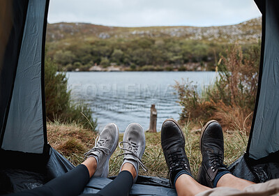 Buy stock photo Shoes, camping and tent with a couple by a lake out in nature while hiking for adventure or travel together. Water, forest and freedom with a man and woman outdoor in the mountain to relax or getaway