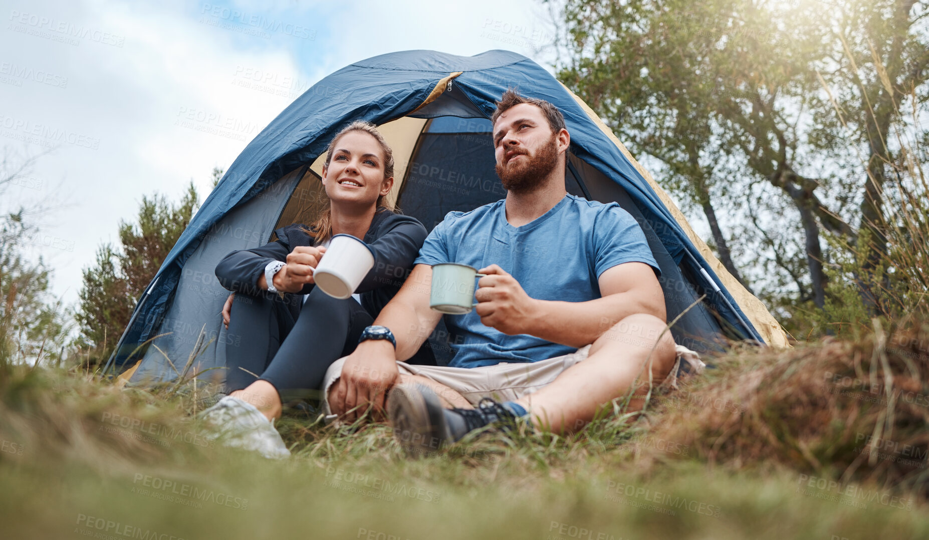 Buy stock photo Camping, tent and nature couple with coffee, tea or hot chocolate relax in outdoor forest or woods. Grass field trees, morning view and camper people bond, talk or enjoy quality time peace or freedom