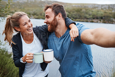 Buy stock photo Selfie, coffee and couple by lake on vacation outdoors in nature, holiday or trip. Tea, relax and happy man and woman in love hug by river taking picture for happy memory or social media post online.