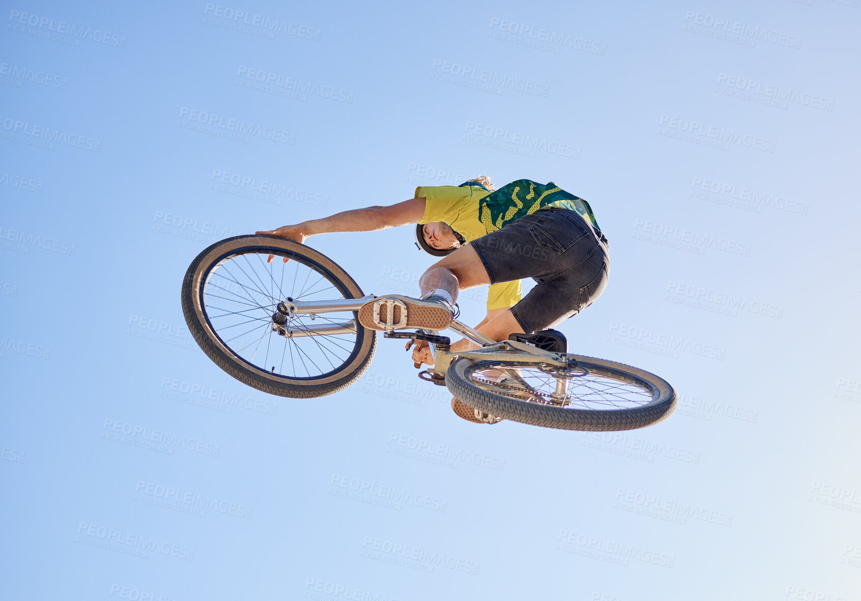 Buy stock photo Bicycle, cyclist man and jump of adrenaline junkie from below riding in a competition with copyspace. Extreme sport, bicycle and cycling man stunt while on bike against a blue sky background 
