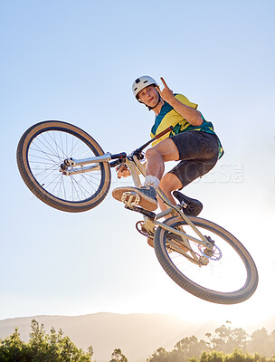 Buy stock photo Bike, jump and rock on hand sign with a man bmx rider jumping over a ramp on a trail or course in nature. Sky, mountain and cycling with a male athlete jumping in mid air during fitness exercise