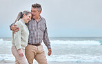 Senior couple, hug and walk on beach for vacation, trip or love in bonding relationship together in the outdoors. Happy elderly man and woman relaxing, walking and enjoying free time by the ocean