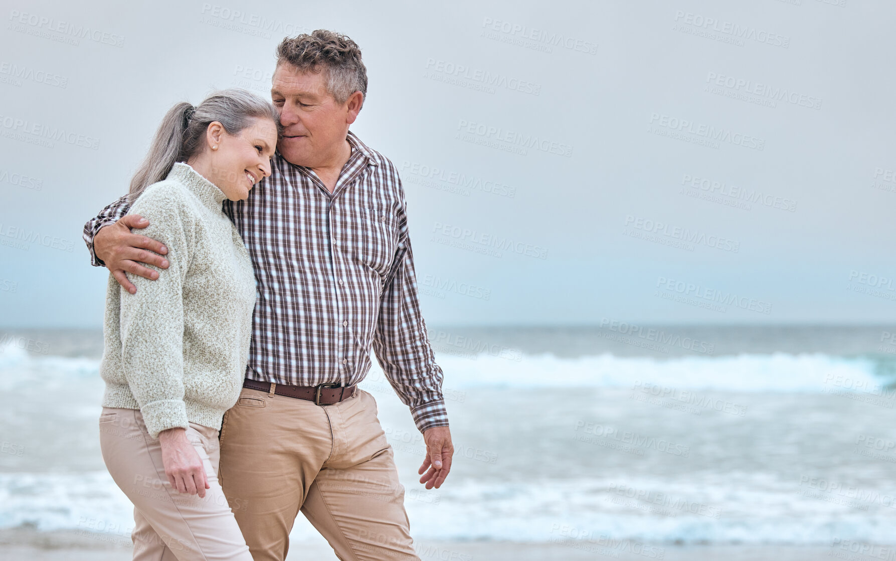 Buy stock photo Senior couple, hug and walk on beach for vacation, trip or love in bonding relationship together on mockup. Happy elderly man and woman relaxing, walking and enjoying free time by the ocean