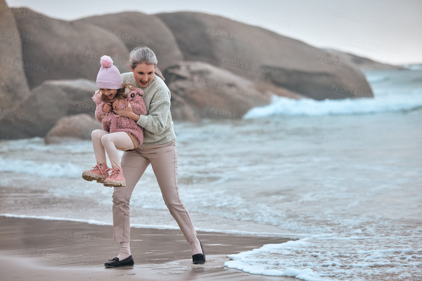 Buy stock photo Grandmother, child and beach fun while on vacation for bonding, love and care while playing with water or waves. Senior woman and girl kid happy about travel, adventure and quality time at sea