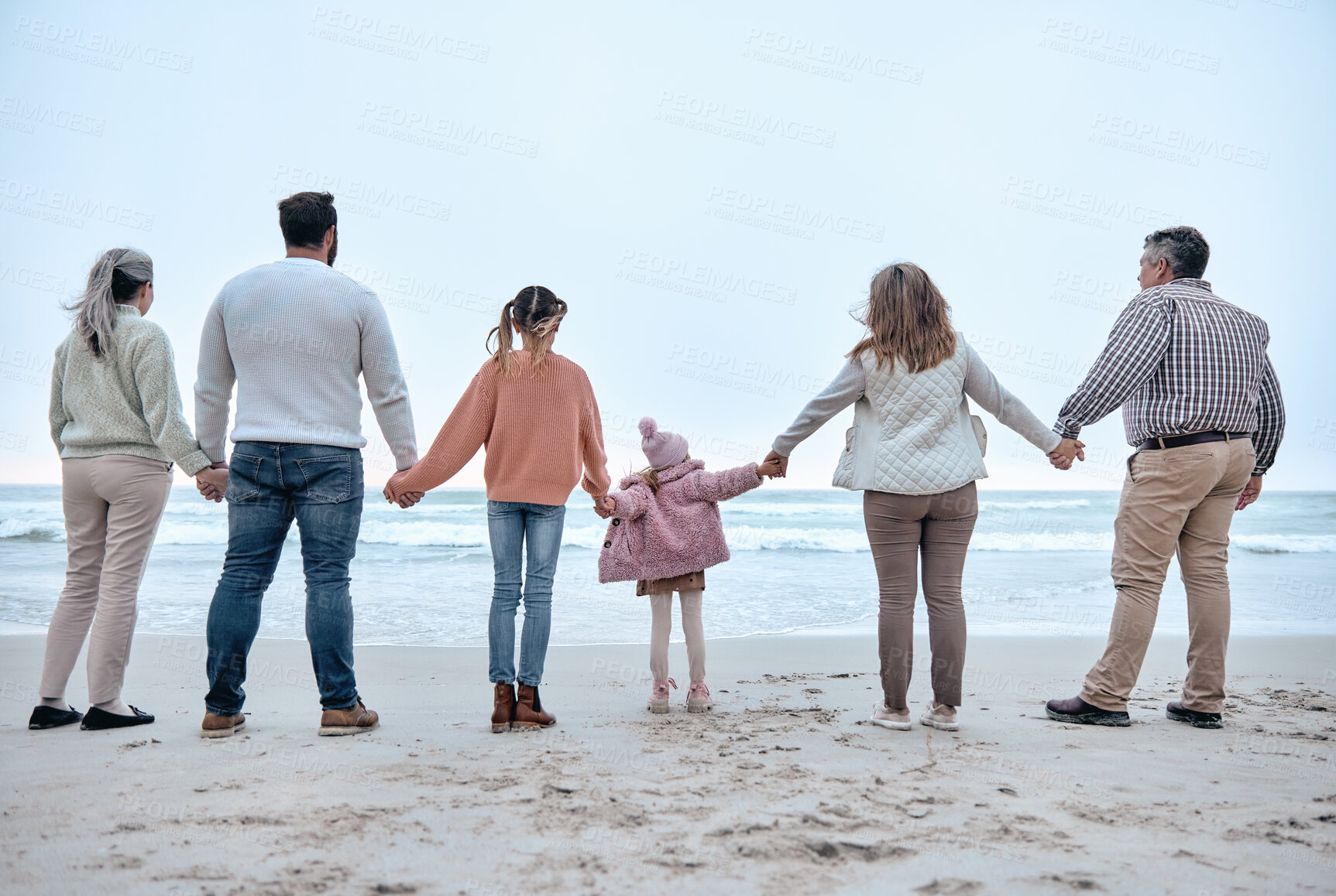 Buy stock photo Family holding hands, beach and adventure with love, trust and relationship, outdoor bonding by the ocean. Parents, grandparents and children, together and travel to the sea for quality time.