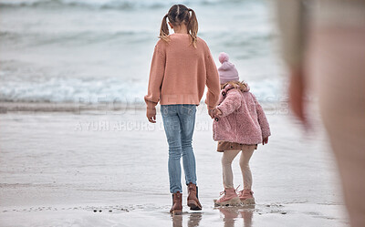 Buy stock photo Children, ocean and holding hands sisters standing on sea sand, relax and watching waves together on vacation. Freedom, fun and young girl with toddler hold hands and play on beach on summer holiday.
