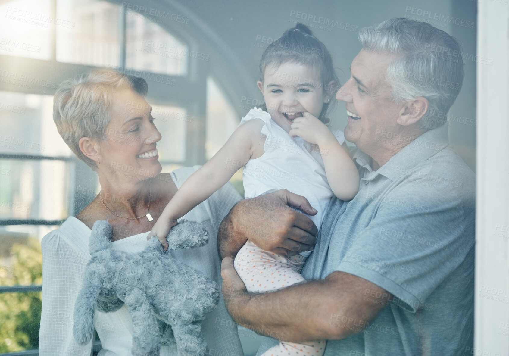 Buy stock photo Family, happiness and love of grandparents for baby in home window for bonding, relax and quality time together. Senior man and woman having fun, care and support for girl on a retirement holiday