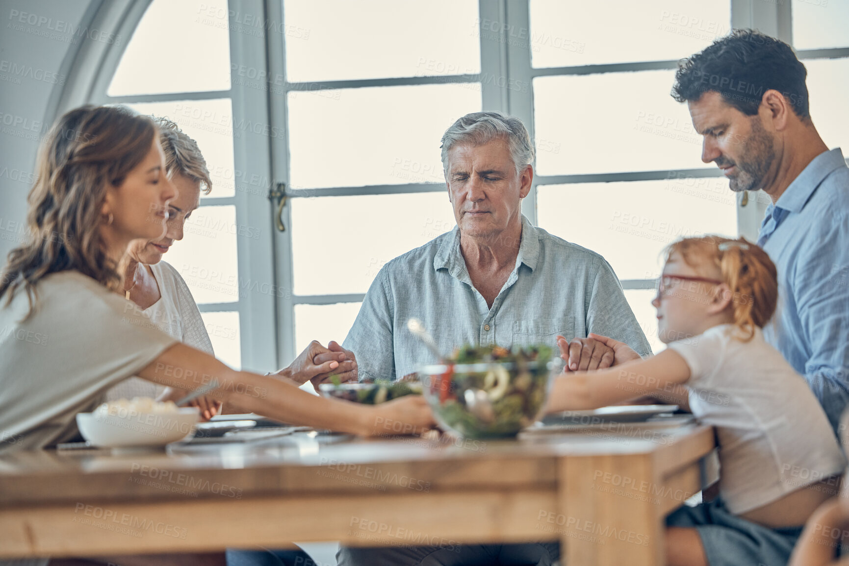 Buy stock photo Big family, food and praying for gratitude and healthy lunch together while holding hands for love, religion and thanksgiving. Men, women and child together for healthy eating at home dining table