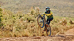 Mountain bike, sport and fitness outdoor with athlete doing stunt for extreme sports on dirt track. Active with bicycle, safety helmet and biker exercise with training in desert location.