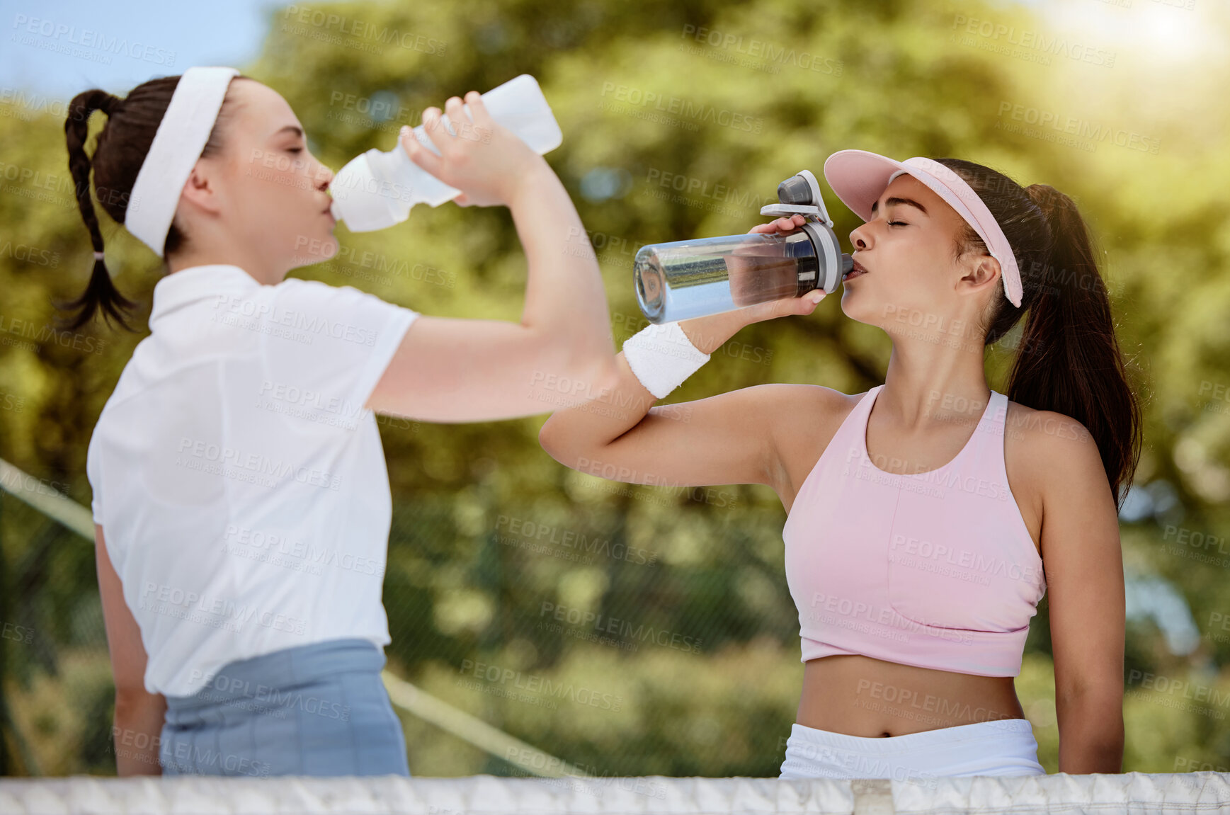 Buy stock photo Tennis, fitness and water, women drinking from bottle on court in hot summer sun at match. Sports exercise, healthy friendship and training workout, girl friends drinking water at competition or game