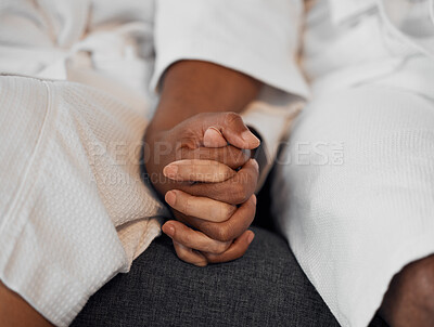 Buy stock photo Closeup spa couple, holding hands and relax in bathrobe together at luxury resort for wellness treatment. Black couple sofa, support trust love and rest for health, care and calm for physical therapy