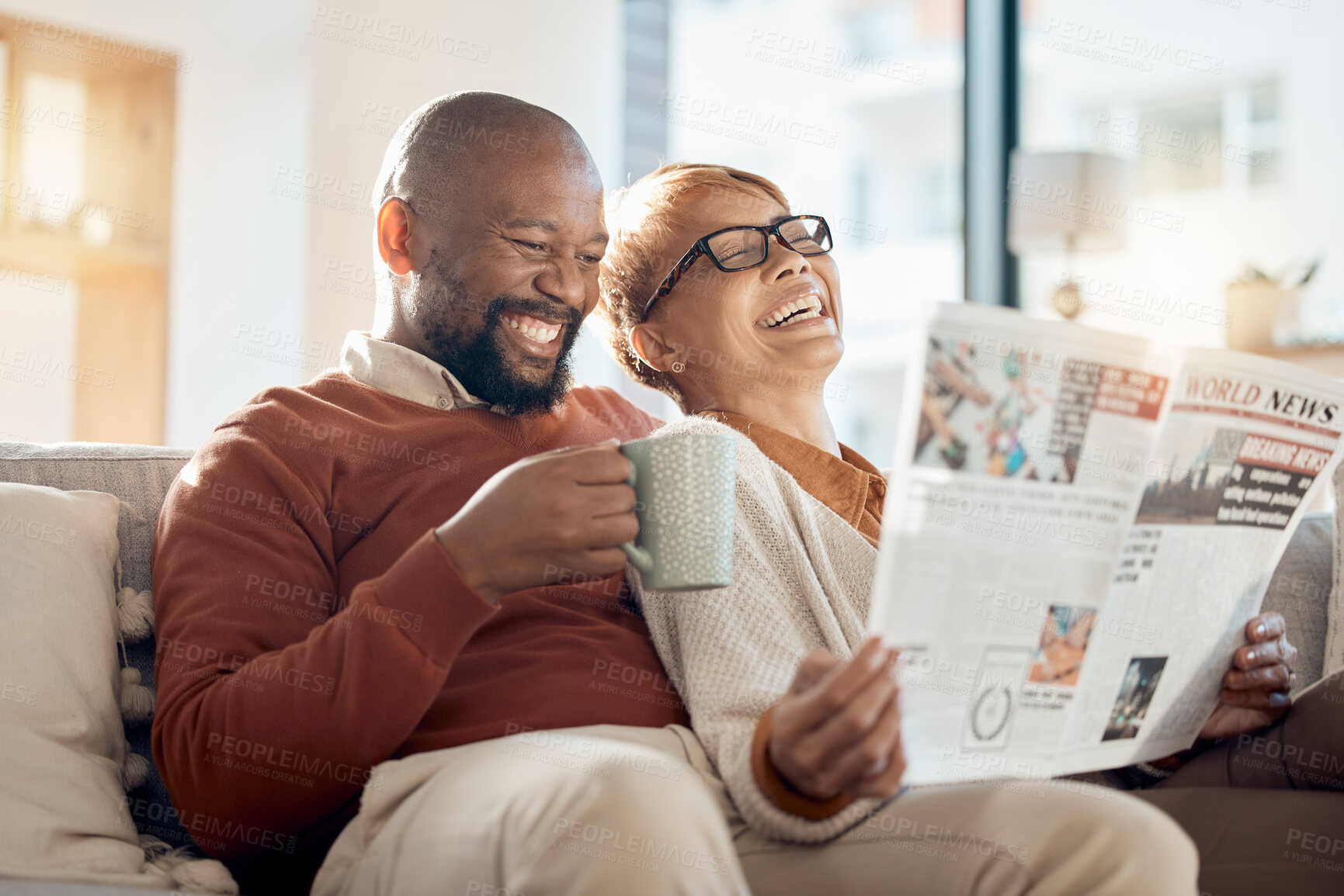 Buy stock photo Happy, smile and couple reading a newspaper while relaxing on a sofa in the living room of their home. Happiness, love and mature interracial people laughing, resting and bonding together at a house.