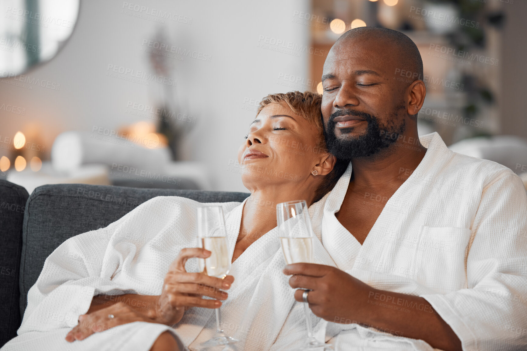 Buy stock photo Mature couple, bonding and champagne on spa date, romantic retreat or resort holiday for marriage anniversary celebration. Black woman, man and alcohol glass on relax salon or hotel living room sofa