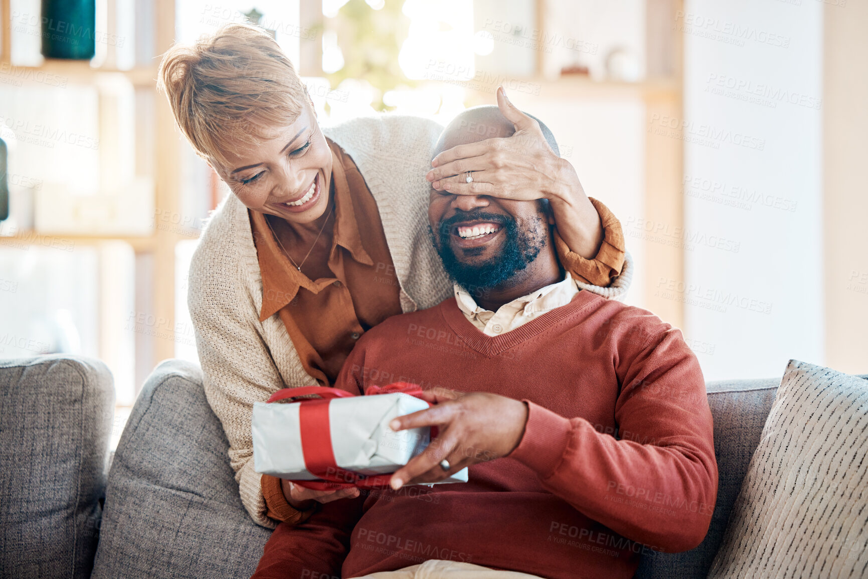 Buy stock photo Black couple, surprise gift and Christmas present in festive summer season from wife with love, happiness and holiday celebration. Black woman, happy man and smile the living room home sofa together 